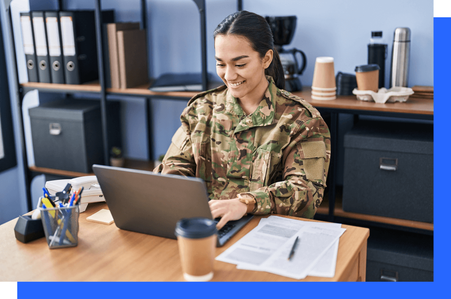 Female solider in camouflage seated at desk working on laptop