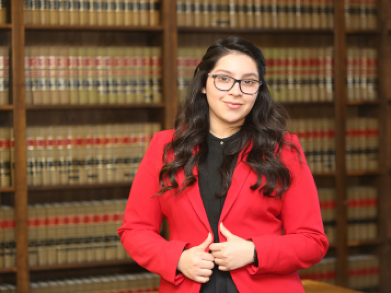 woman in red smiling in front of a full wall bookcase