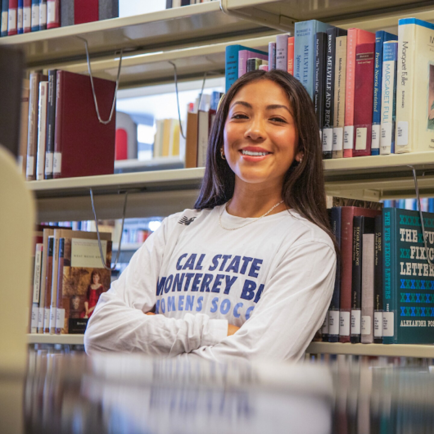 A close-up of a smiling female CSUMB student with her arms crossed.