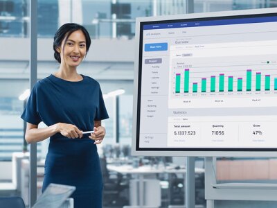 A business professional presents data insights on a large screen to a team, highlighting key aspects of business analysis and performance metrics.