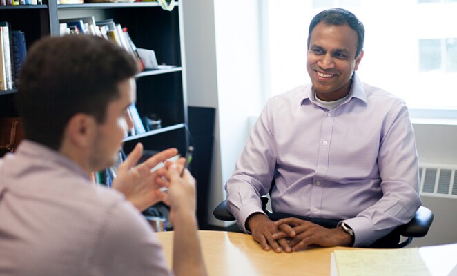 Two men smiling and speaking in an office