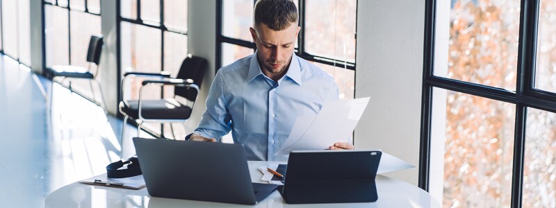 Businessman reviewing documents while using a laptop