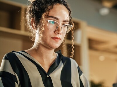 Woman wearing button down striped top studying at her laptop