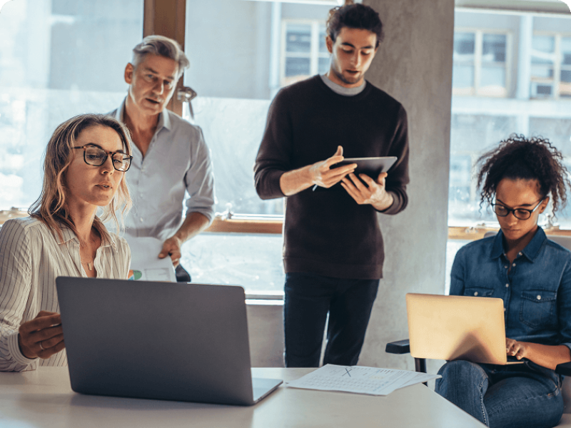 Two men and two women collaborating in conference rooms with electronic devices