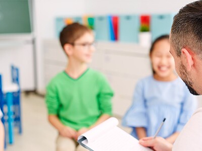 smiling kids sitting in a classroom with a school counselor