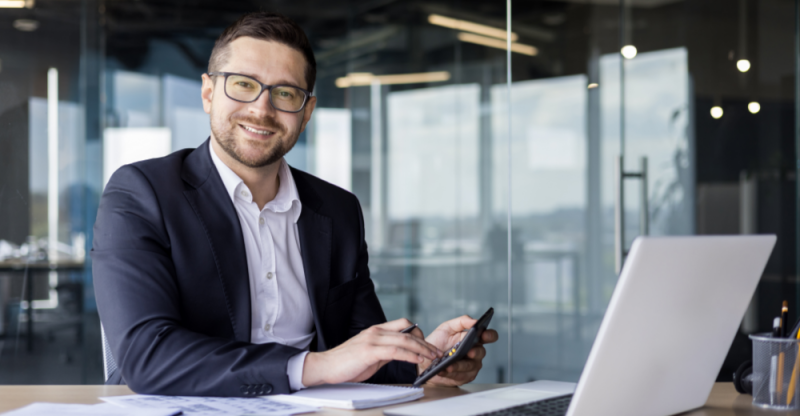 Man using calculator in front of laptop computer