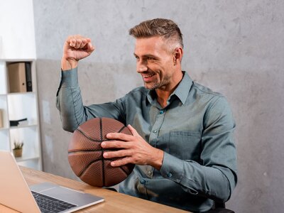 Cheerful sports agent holding a basketball while encouraging a client in a meeting.