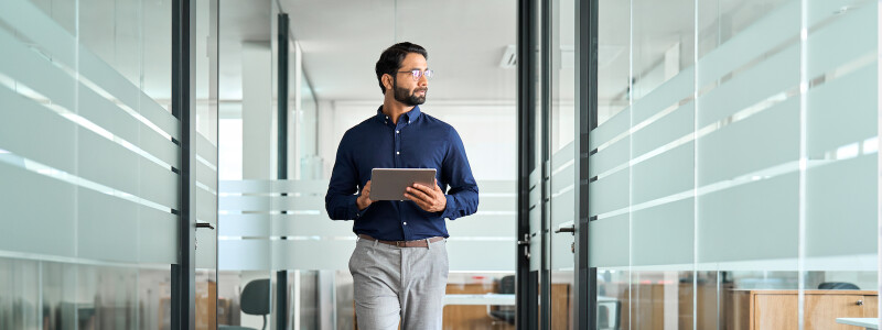 Busy professional businessman going in hallway holding digital tablet thinking of work