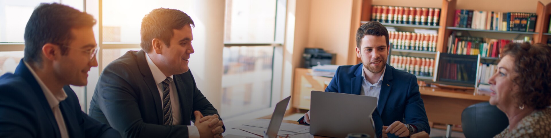 a group of professional conduct a meeting in a law office while working on laptops