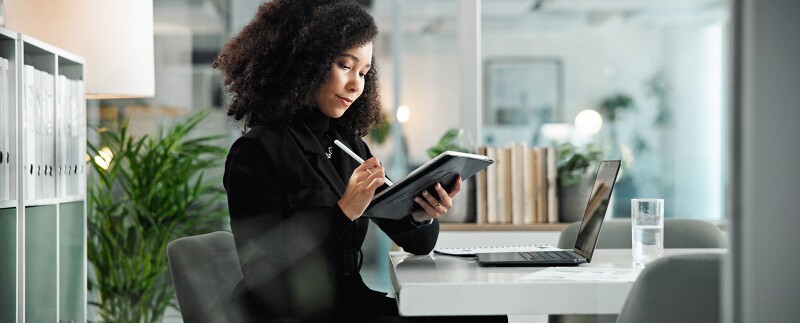 Health care compliance officer working on her tablet and laptop
