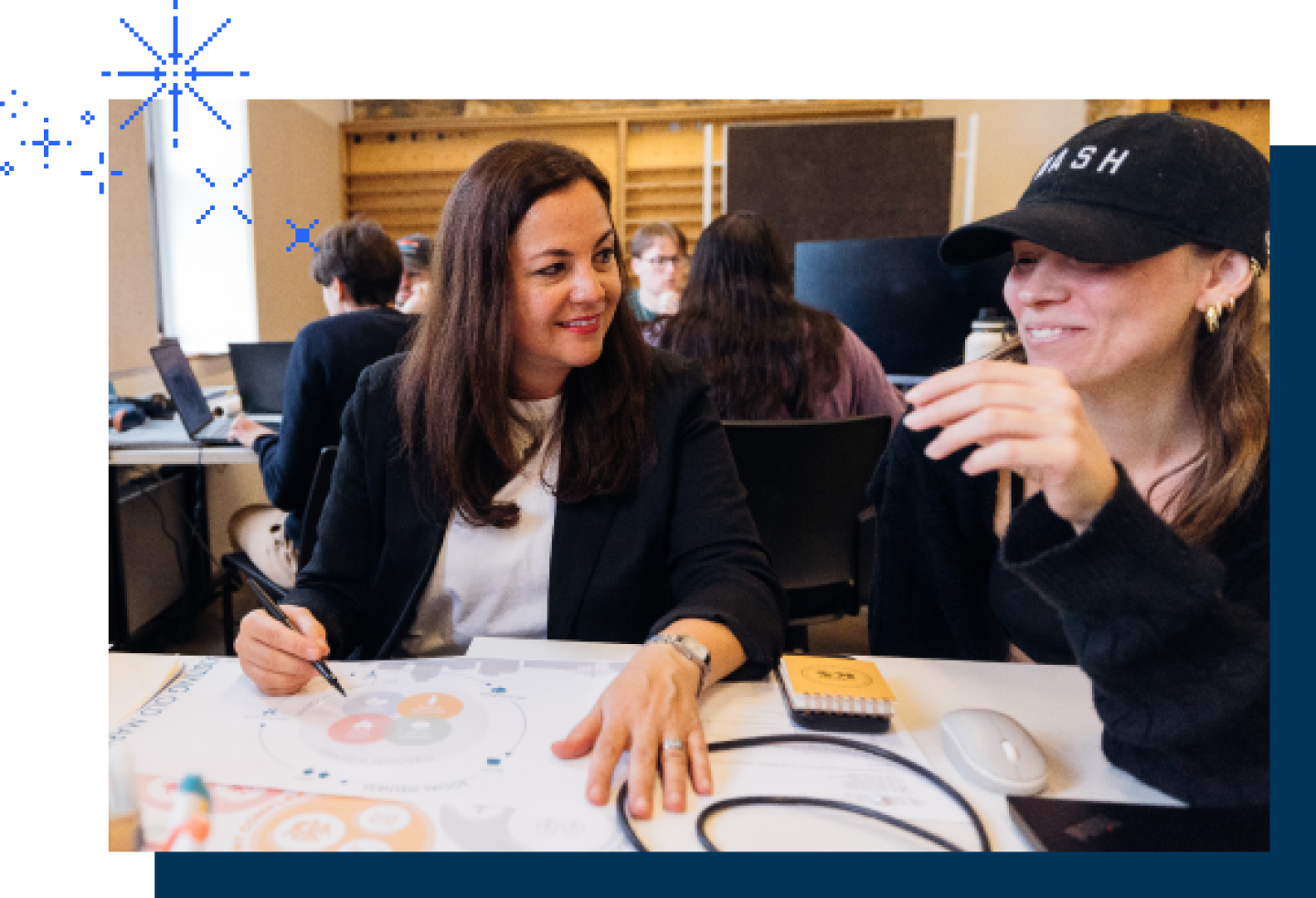 Two female teaching professionals discuss teaching lessons at a table.