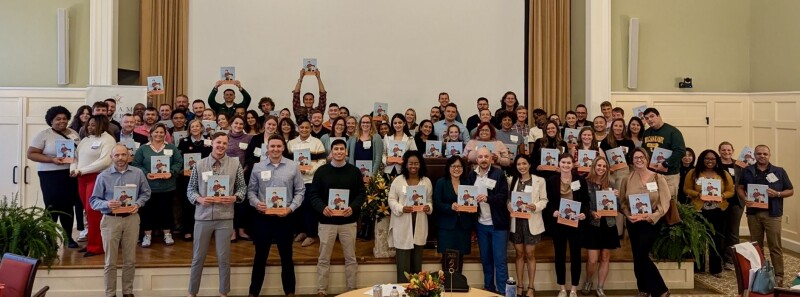 Residency Weekend attendees pose in a group photo with their copies of AI the Magic Box book.