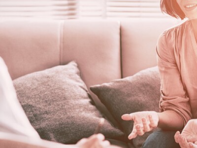 Two women sit facing each other and talking in a counselor's office.