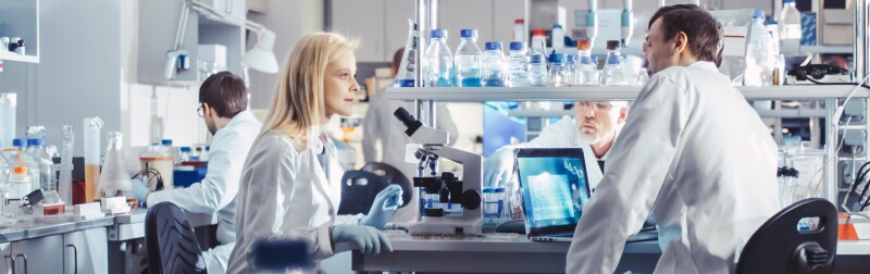 Group of Medical Researchers in White Coats are having a passionate discussion in a modern high-tech research laboratory.