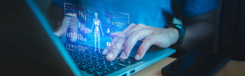 A futuristic screen is projected above a keyboard, illustrating a human body with various metrics displayed alongside it.