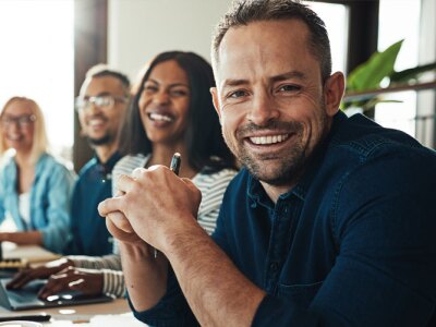 Smiling mature businessman sitting with colleagues in an office.