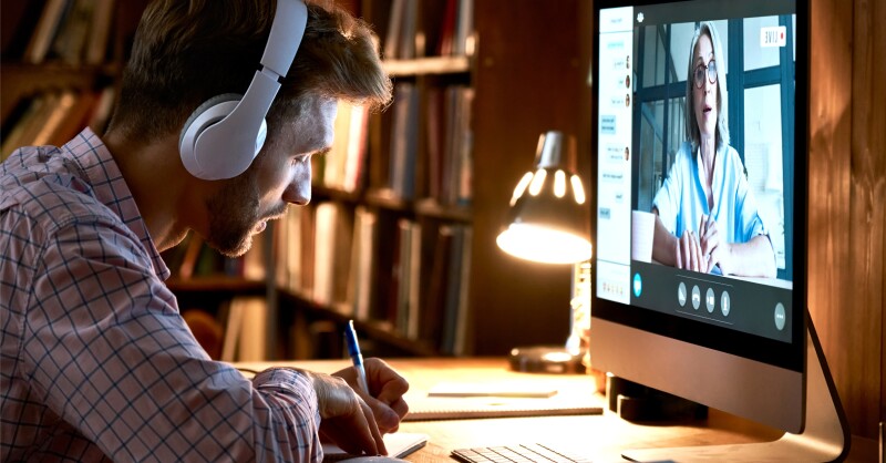 Male student wearing headphones watching webinar, online class