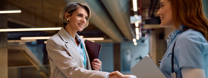 A health services administration professional and a healthcare provider shake hands.