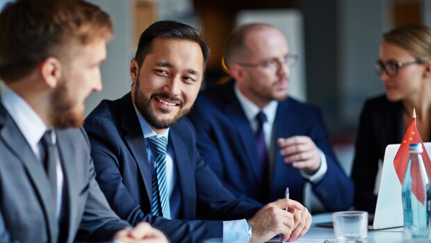 three-man-and-a-woman-smiling-in-suits-talking-bottle-on-table-red-flag