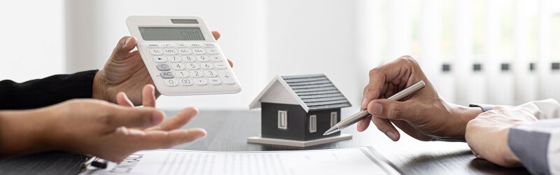 Toy house and calculator being used in real estate finance discussion