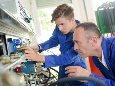 two men in blue working on a machine