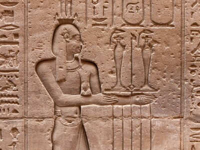 The image features Egyptian hieroglyphs carved into a stone wall.