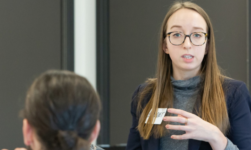 Woman in business attire and nametag speaking to students