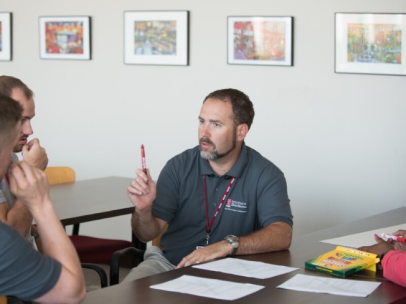 Three male colleagues seated at table talking