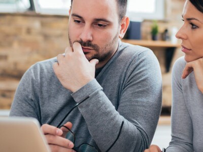 Couple managing finances in front of a laptop in their kitchen.
