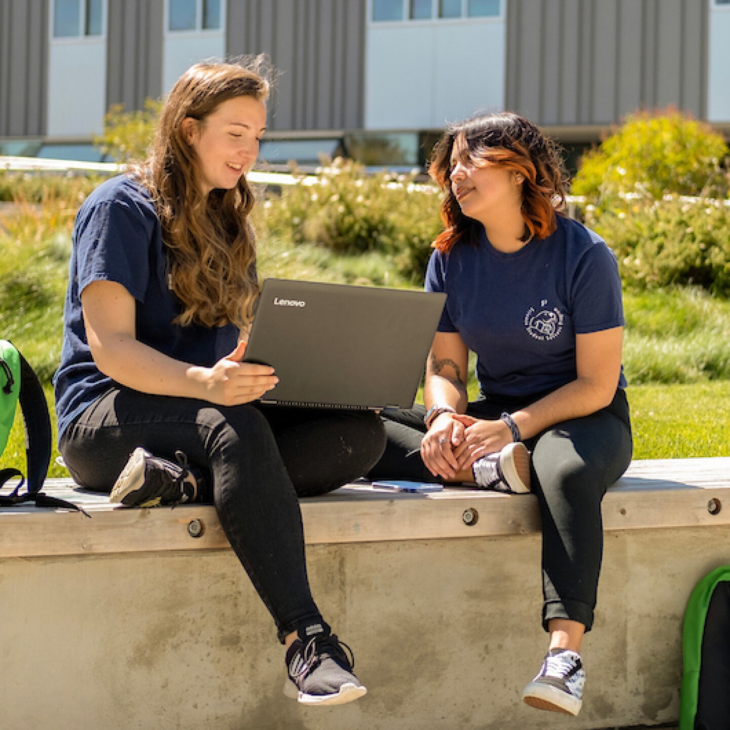 A female CSUMB student tutors another CSUMB student while sitting in the common grounds.