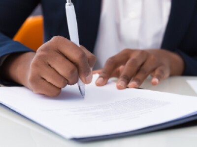 Professional in suit signs document on desk