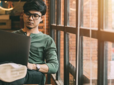 guy in green shirt with legs up on chair working on laptop