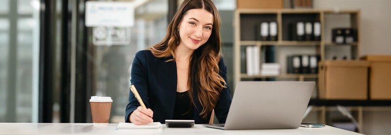 Woman with a laptop, calculator and coffee taking notes