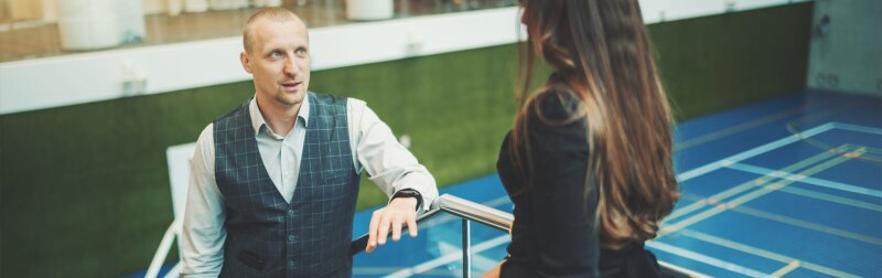 A lively conversation between two business partners with selective focus on a man entrepreneur with a laptop talking to his female colleague.