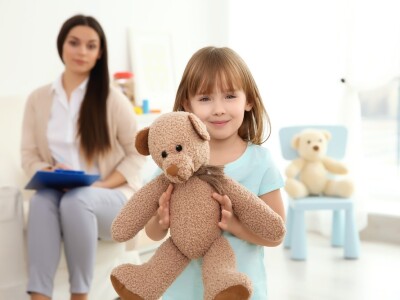 social worker sitting on a bench observing a child holding a teddy bear