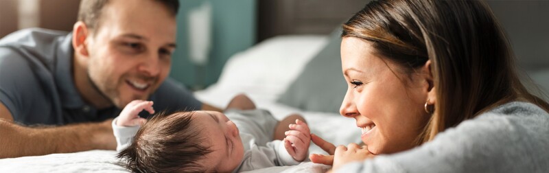 A couple with newborn baby on a bed