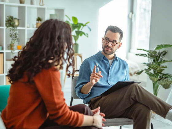 A male mental health counselor discusses session topic with a female patient.