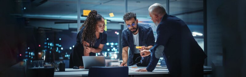 A diverse team of executives discuss financial investments during a night meeting.