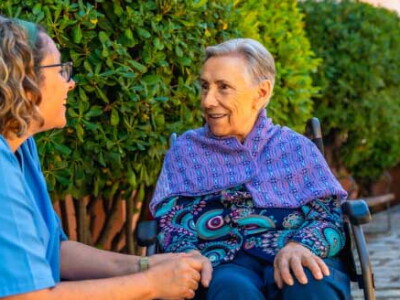 woman in wheelchair holding hands with nurse