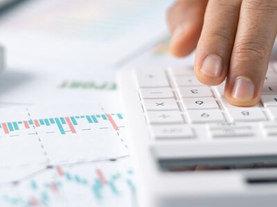 Woman working on desk using a calculator, calculating finances.