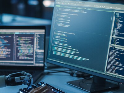 Engineer coding with a prosthetic robot arm.