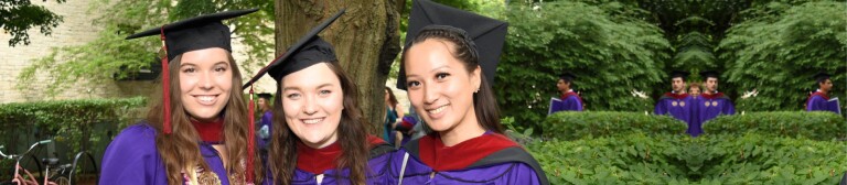 Three IMC graduates smile in their cap and gown