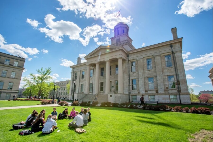 Circle of students seated outdoors on Iowa campus