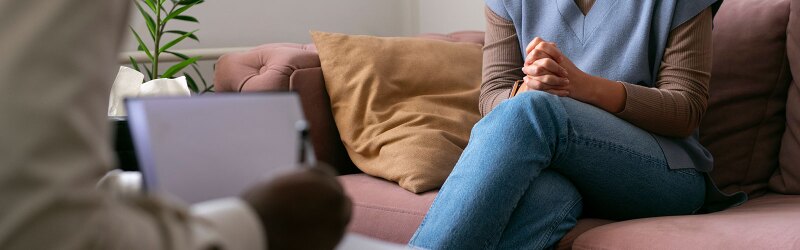 person sitting on pink couch clasping hands in session