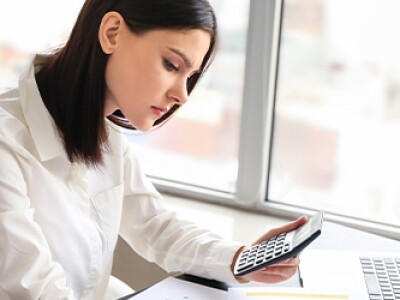 Female accountant working at her desk with calculator and computer