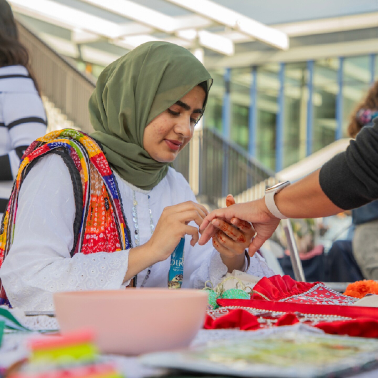 A volunteer carefully applies henna during a cultural celebration, sharing tradition and creativity with the community.