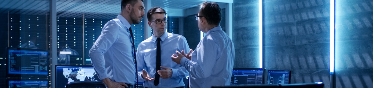 Three professionals in discussion in operations room