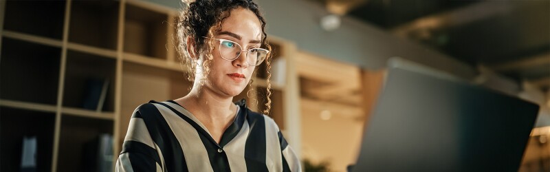 Woman wearing button down striped top studying at her laptop