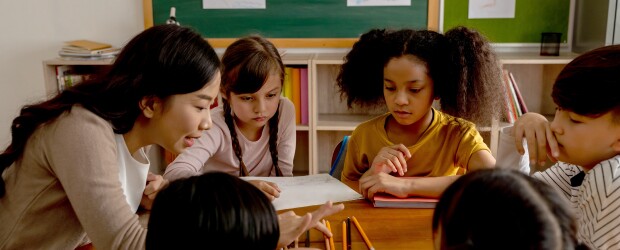 woman-teaching-five-kids-green-chalkboard-in-background