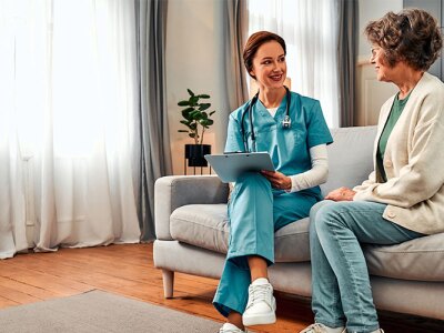 geriatric care nurse sitting in session with elderly female patient